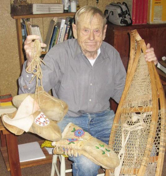 John Macfie holding snowshoes, mukluks and mitts